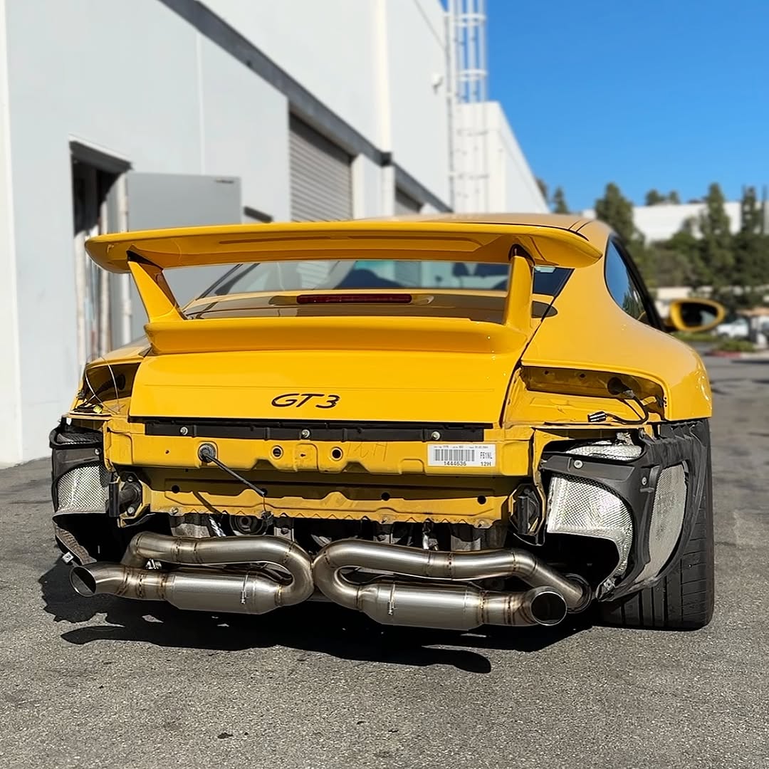 Yellow GT3 car with a large rear wing on a street.