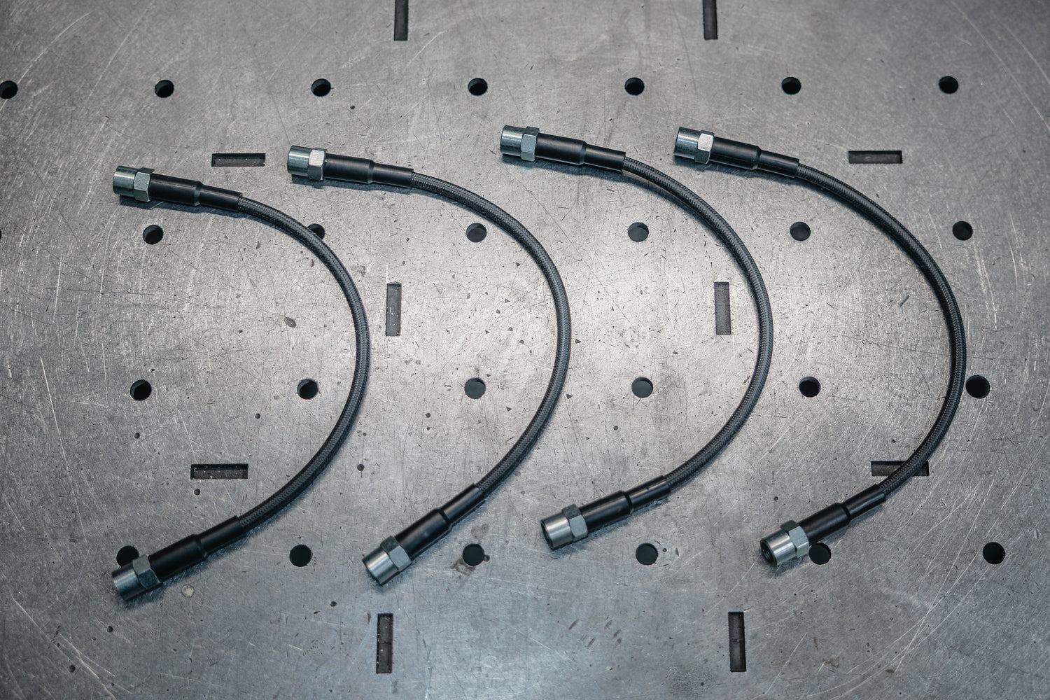 Three flexible metal hoses on a metallic surface