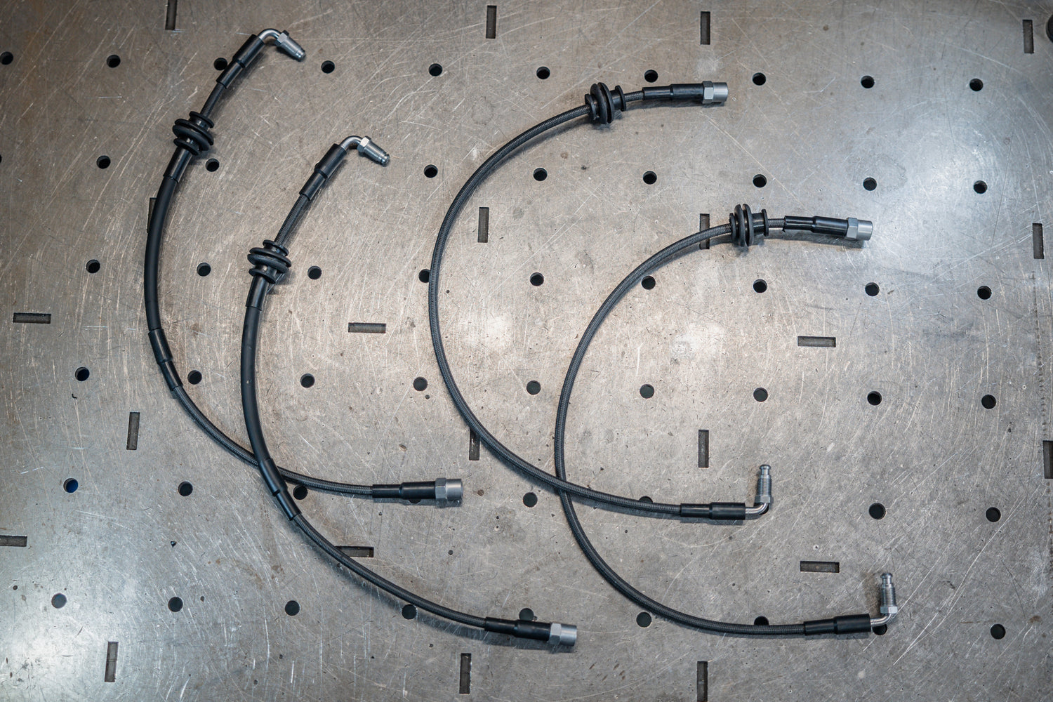 Three metal brake hoses on a perforated metal surface