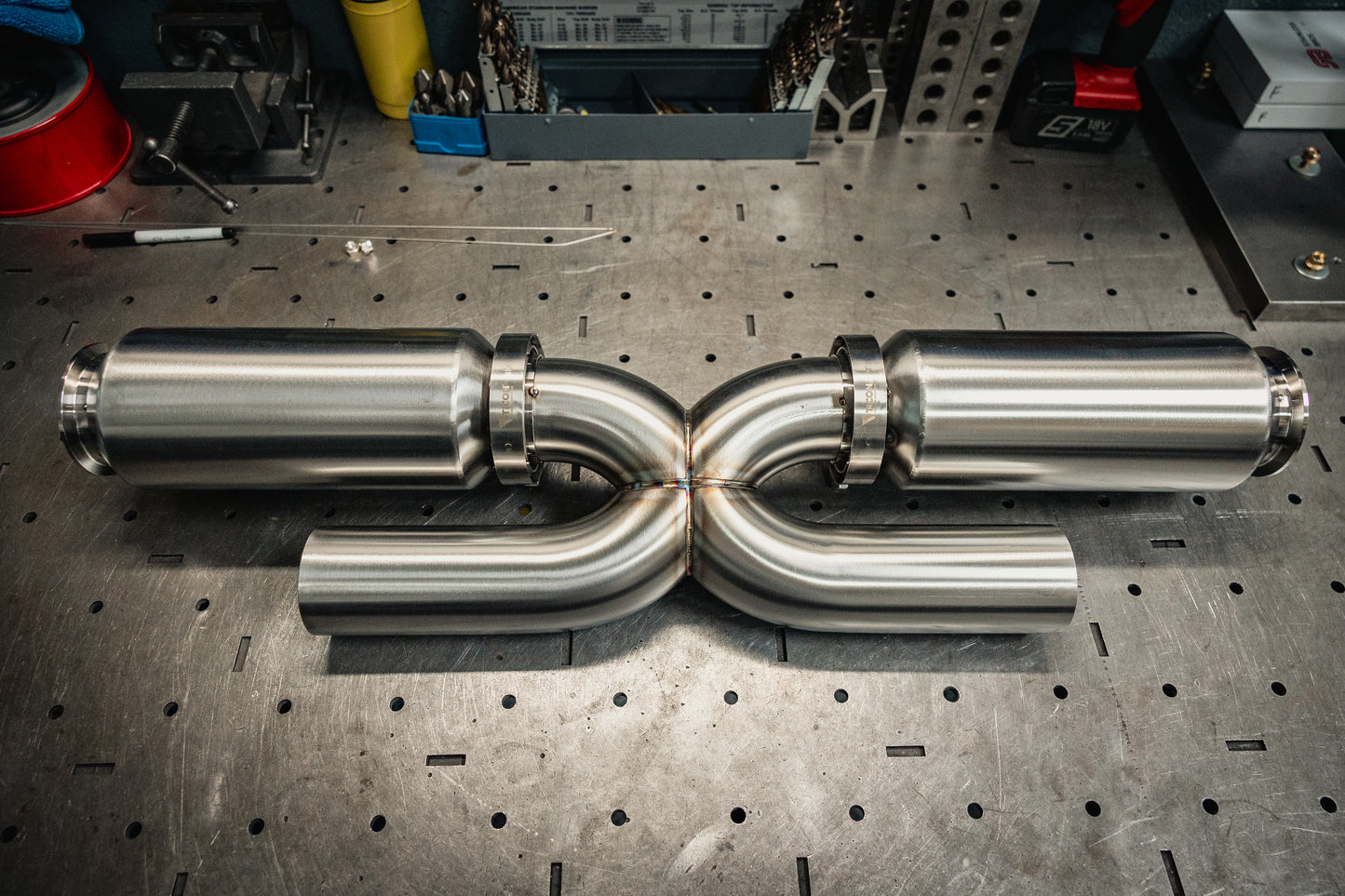 Metallic exhaust pipes on a workshop table with tools in the background
